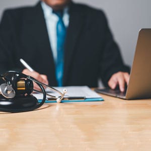 Attorney at a desk with stethoscope and laptop, representing California Personal Injury Claims - The Law Man Group, APC